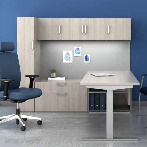 Modern office setup with desk, chair, and storage cabinets against a blue wall. Kansas City Office Design.