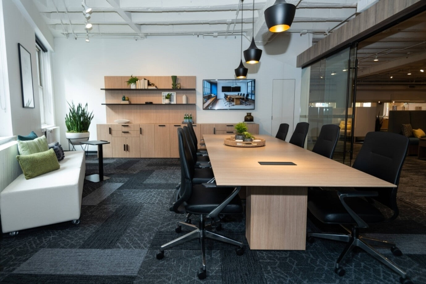 Modern office space with a long wooden table, AIS Auburn Conference chairs, and a TV on the wall. Kansas City Office Design