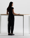 Woman in black outfit standing at a modern Humanscale eFloat Quattro standing desk with a white background. Kansas City Office Design.