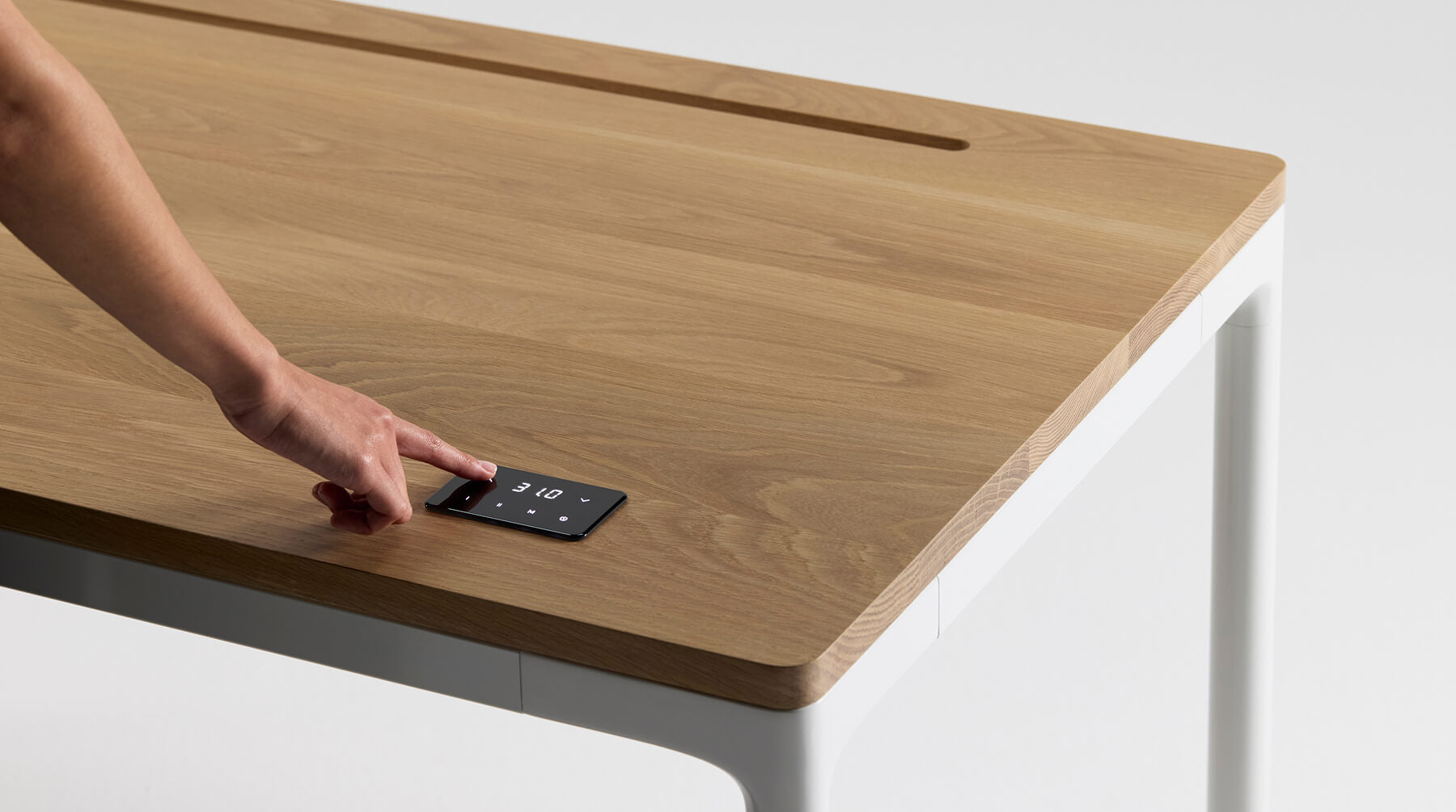 Hand interacting with a digital display on a wooden surface of the Humanscale eFloat Quattro Height Adjustable Table. Kansas City Office Design.