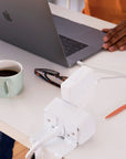 Person using a laptop on a desk with a mug, glasses, and pen. Showing the back side of the EON power module. Kansas City Office Design.