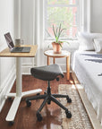 Humanscale saddle stool in a small home office with a desk, chair, laptop, and decor in a bedroom. Kansas City Office Design.