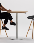 Person sitting at a Humanscale Float Gather table with black stools on a white background. Kansas City Office Design.