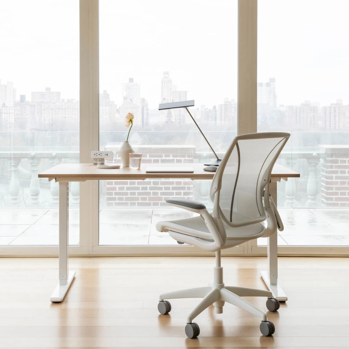 Humanscale World Chair with white mesh, white frame at a height adjustable desk overlooking city  — back view – Kansas City Office Design