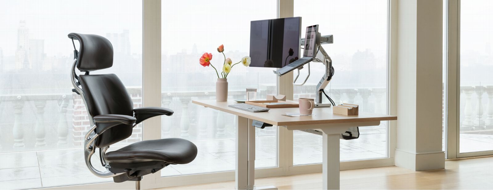 Modern office setup with ergonomic chair, adjustable desk, and computer monitor in a bright room. Kansas City Office Furniture.