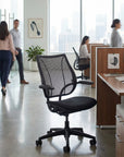 Black office chair in an office setting with people and desks in the background. Kansas City Office Design.