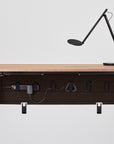 Wooden desk with black metal frame and a lamp on a white background. This includes the Humanscale NeatTech Cable Management tray installed under the surface. Kansas City Office Furniture.