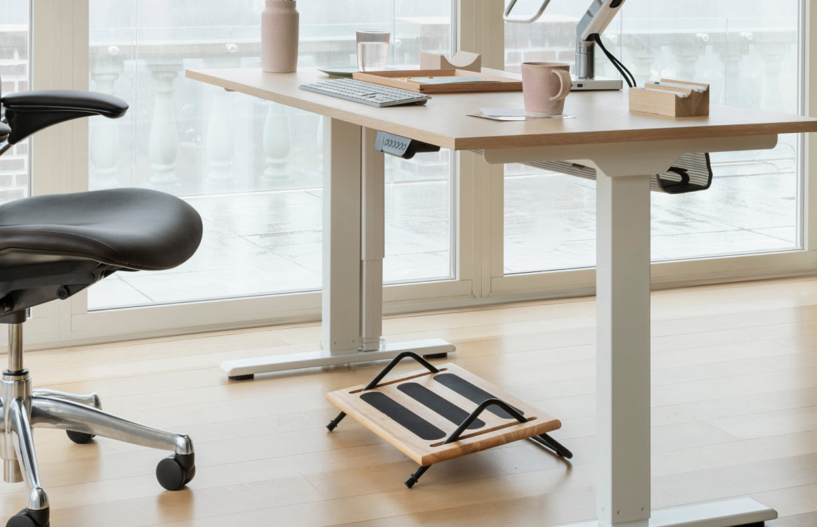 Ergonomic desk setup with adjustable chair and desk, and a Humanscale footrest in a bright room. Kansas City Office Design. 