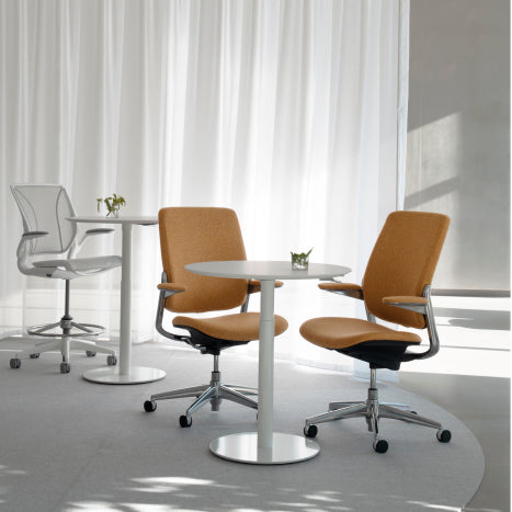Modern office chairs and Humanscale Float Gather 30" round tables in a bright room with white curtains. Kansas City Office Design.