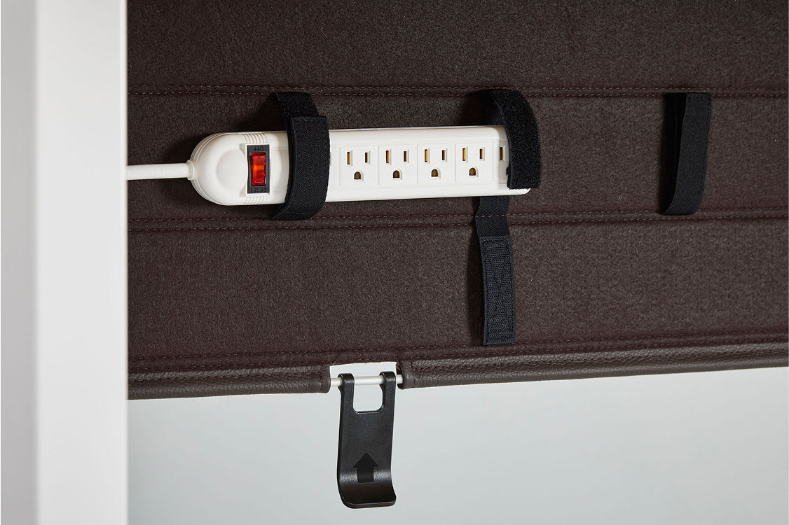 Closeup of the Humanscale NeatTech Cable Management tray with a Power strip with multiple outlets attached to a brown surface using black straps. Kansas City Office Furniture
