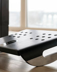 Humanscale black footrest on a wooden floor with large windows in the background. Kansas City Office Design. 