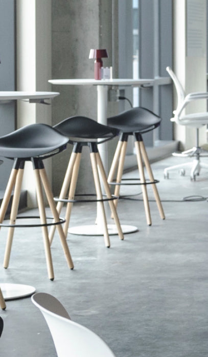 Black stools with wooden legs in a modern interior setting with Humanscale Float Gather tables. Kansas City Office Design.
