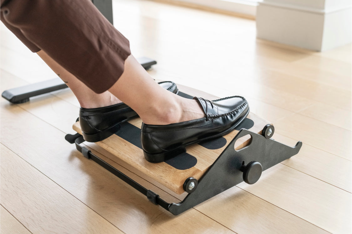 Person using a Humanscale footrest on a wooden floor. Kansas City Office Design.
