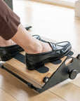 Person using a Humanscale footrest on a wooden floor. Kansas City Office Design.