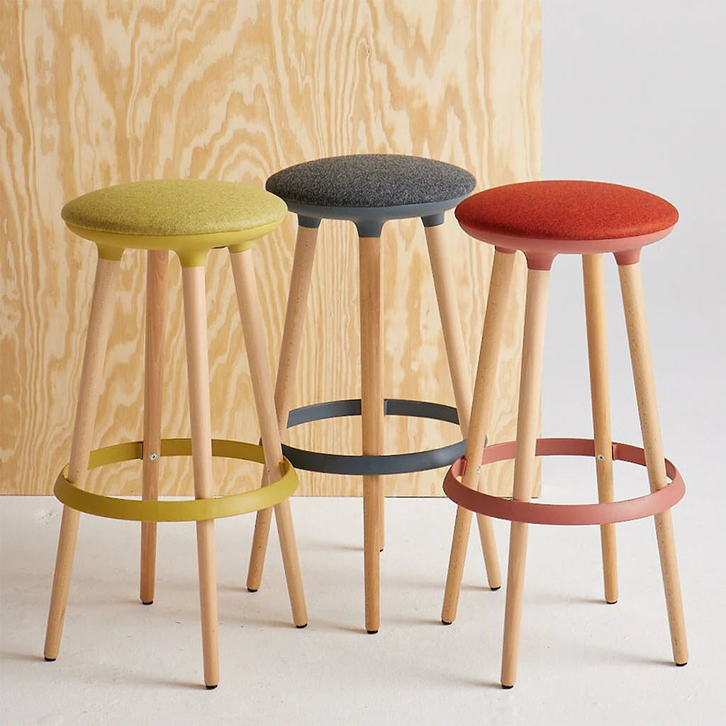 Three Via Joi bar stools with colorful seats against a wooden and white background. Kansas City Office Design.