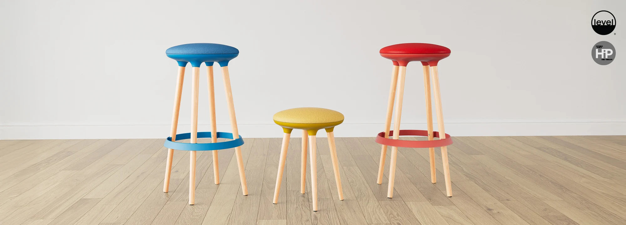 Three colorful Via Joi stools on a wooden floor with a plain background. Kansas City Office Design.