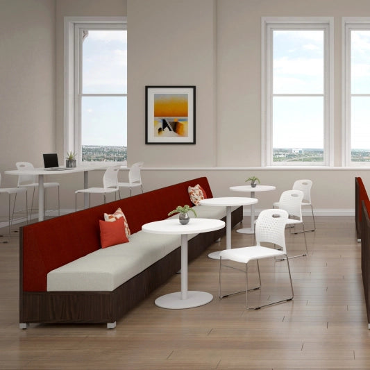 Modern office break room with red and white furniture, large windows, and a framed picture on the wall. Kansas City Office Design