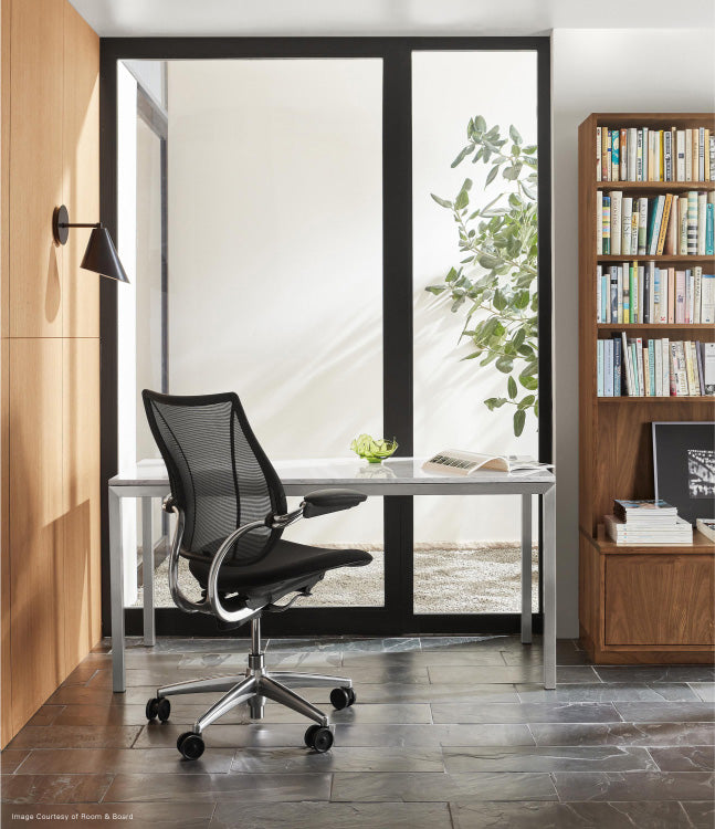 Modern office setup with a black Humanscale Liberty chair, desk, and bookshelf. Kansas City Office Design.