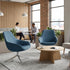 Modern office waiting area with blue chairs, a wooden table, and people sitting. Kansas City Office Design.