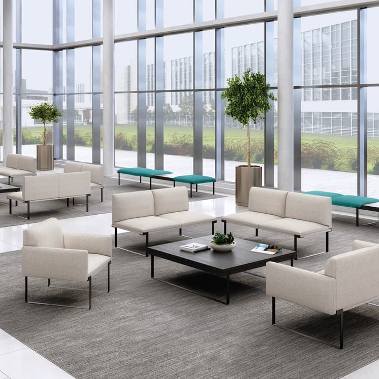 Modern office lounge area with beige SitOnIt Cameo sofas, coffee tables, and large windows. Kansas City Office Design