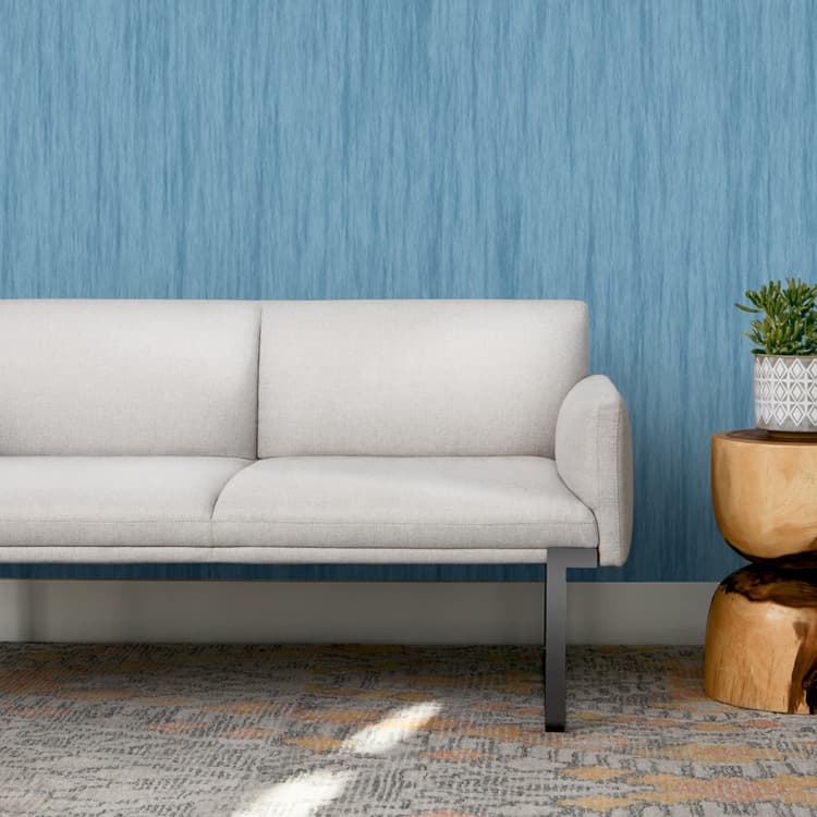 Gray SitOnIt Cameo sofa in a room with blue textured wallpaper and a wooden side table. Kansas City Office Design