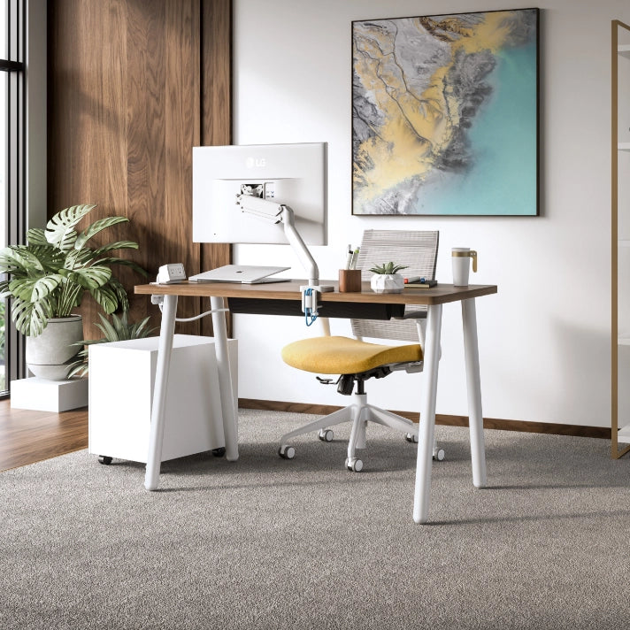 Modern office desk with chair, computer monitor, and decor in a well-lit room. Kansas City Office Design.