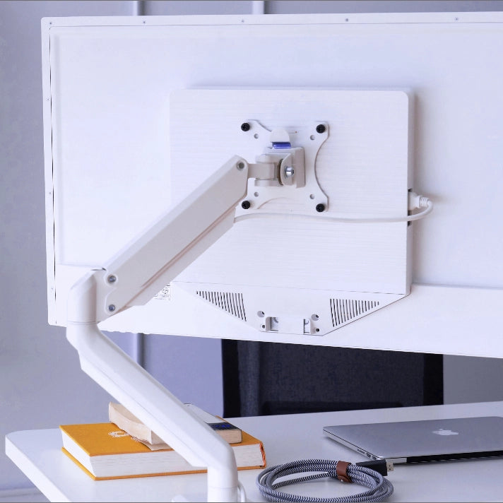 White adjustable SitItOn Mobio monitor stand on a desk with books and a laptop. Kansas City Office Design.