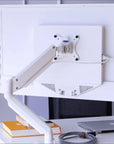 White adjustable SitItOn Mobio monitor stand on a desk with books and a laptop. Kansas City Office Design.