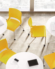 Yellow chairs around white round tables with laptops on a textured floor. Kansas City Office Design.