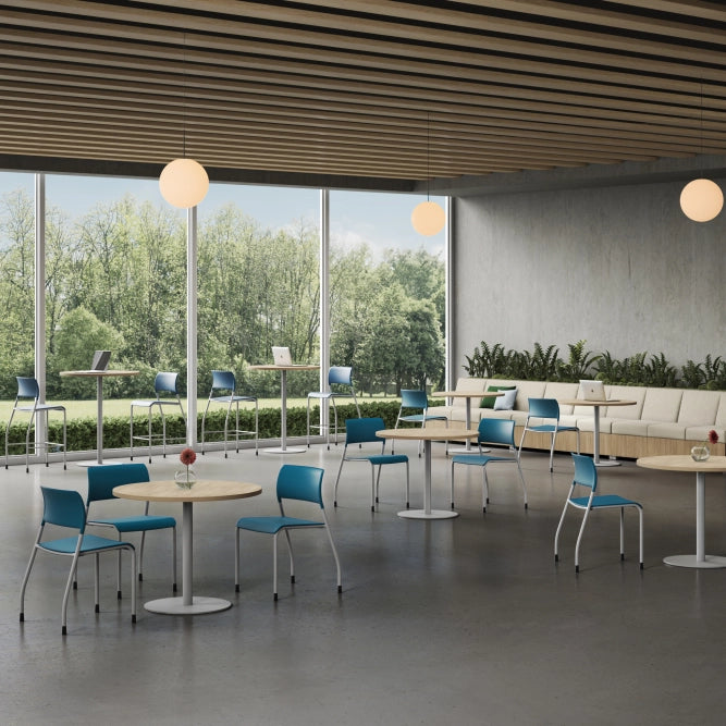 Modern indoor setting with tables, chairs, and a large window view of greenery. Kansas City Office Design