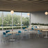 Modern indoor setting with tables, chairs, and a large window view of greenery. Kansas City Office Design