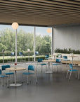 Modern indoor setting with tables, chairs, and a large window view of greenery. Kansas City Office Design