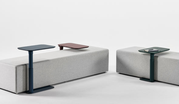 Two modern gray benches with adjustable Humanscale Float micro tables on a white background. Kansas City Office Design.