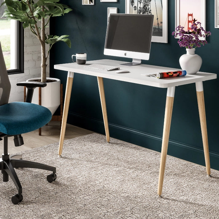 Modern office setup with a white SitOnIt Reya desk, computer monitor, and chair against a dark blue wall. Kansas City Office Design.