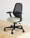 Ergonomic office chair with mesh backrest and beige seat on a wooden surface.