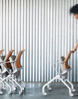 Woman arranging office chairs against a striped wall. Kansas City Office Design.