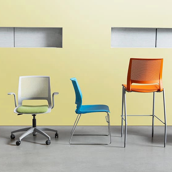 Three colorful chairs against a yellow wall. Kansas City Office Design.
