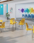 Modern office space with yellow chairs and tables, colorful abstract art on the wall. Kansas City Office Design.