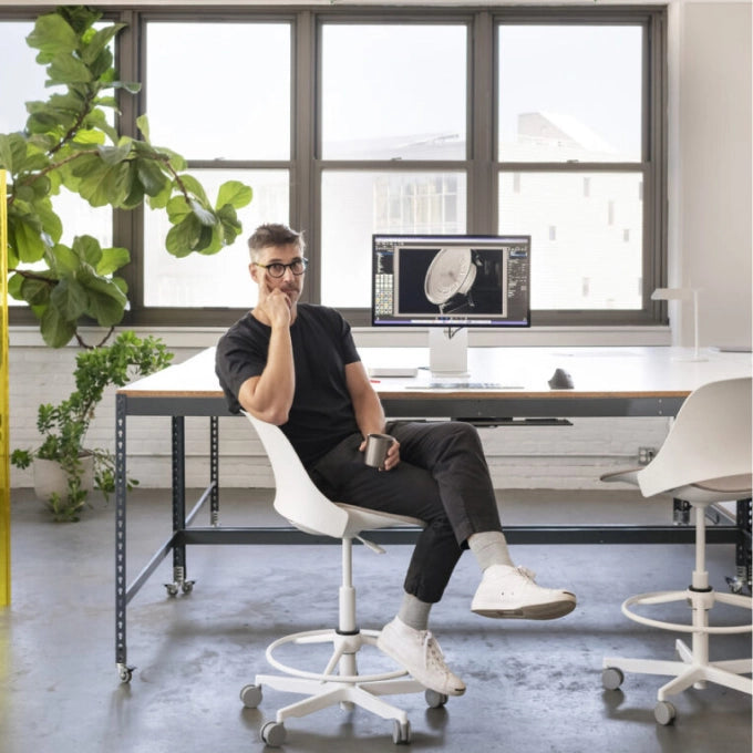 Man sitting at a desk in a modern office with a computer and plant. Kansas City Office Design