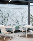 Modern office setting with white tables and chairs against a white brick wall with greenery. Kansas City Office Design